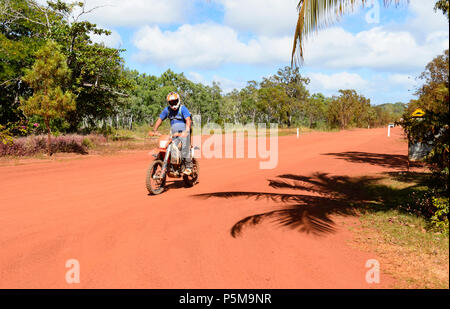 Motorbiker reiten ein Dirt Bike auf einem entfernten Red dirt road, Cape York Halbinsel, Far North Queensland, FNQ, QLD, Australien Stockfoto