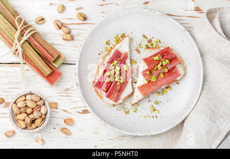 Gebackene Rhabarber. Toast mit Frischkäse und Pistazien. Leckeres und gesundes Frühstück. Selektiver Fokus Stockfoto