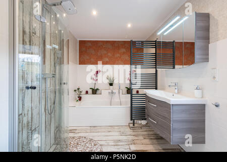 Modernes Bad im traditionellen Stil mit Waschbecken, Badewanne, Dusche aus Glas und schwarzem Handtuchtrockner. Stockfoto