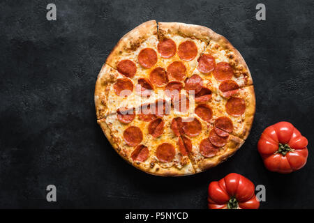 Pepperoni Pizza auf Schwarz konkreten Hintergrund. Amerikanische Pepperoni Pizza, Ansicht von oben Stockfoto