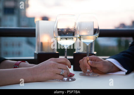 Anstoßen mit Weißwein und Toasten im Sonnenuntergang Stockfoto