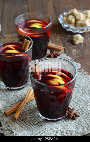 Wein mit Zitronenschale in Gläsern auf hölzernen Hintergrund Glühwein Stockfoto