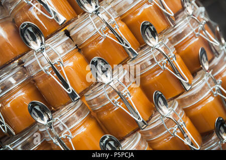 Kleine Gläser gesalzene Butter Caramel mit Löffeln gestapelt Stockfoto