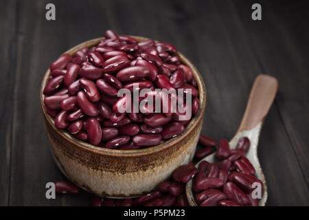 Bohnen oder rote Bohnen in eine keramische Schüssel und in einem keramischen Löffel auf Holztisch. Stockfoto