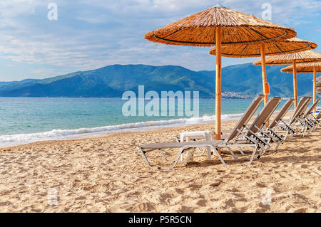 Grau Stroh Regenschirm auf den schönen Strand und das Meer mit brennenden Sonne Stockfoto