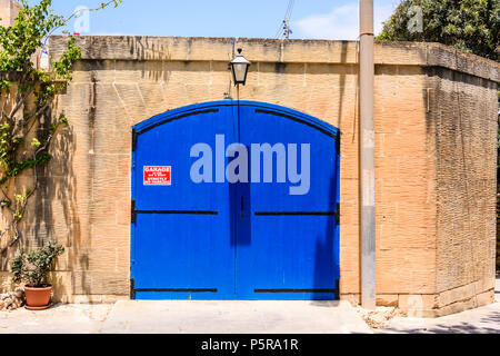 Blau Garagentor in Gozo, Malta mit einem Schild, kein Parkplatz. Stockfoto