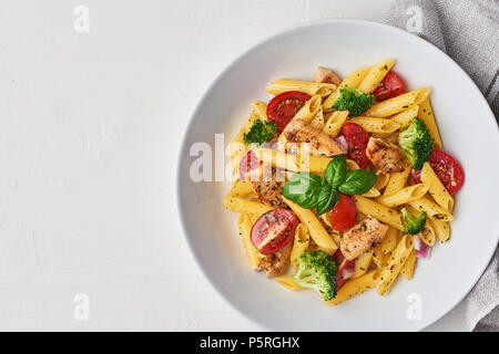 Italienisches Essen. Flach der fusilli Pasta Salat mit Italienischem Dressing, Tomaten, Brokkoli und Basilikum auf weißem Hintergrund. Ansicht von oben, kopieren. Stockfoto