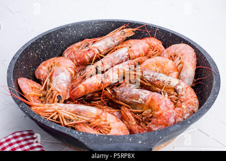 Große Garnelen gebraten in der Pfanne. Auf einem weißen Tisch. Vom Mittagessen mit Meeresfrüchten. Freier Platz für Text. Platz kopieren Stockfoto