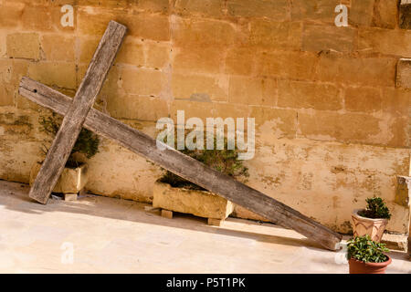 Ein großes hölzernes Kreuz liegt propped gegen eine Wand außerhalb eines Hauses in Gozo, Malta. Stockfoto