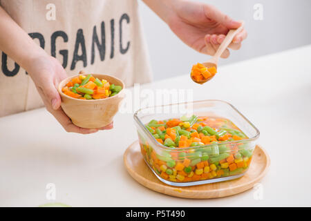 Schöpfkelle aus gedämpftem frisch geernteten jungen Gemüse, einschließlich Crinkle cut geschnittene Karotten, Erbsen und Kartoffeln für eine gesunde Begleitung zum Abendessen Stockfoto