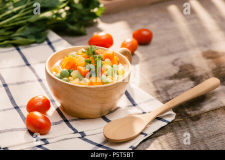 Schöpfkelle aus gedämpftem frisch geernteten jungen Gemüse, einschließlich Crinkle cut geschnittene Karotten, Erbsen und Kartoffeln für eine gesunde Begleitung zum Abendessen Stockfoto