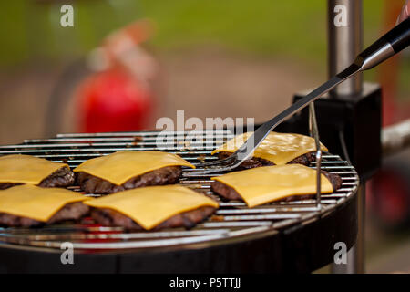 Vorbereitung der Cheeseburger auf Familie BBQ Tag Stockfoto