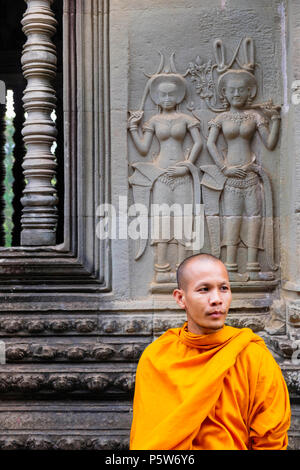 Buddhistischer Mönch vor Schnitzereien tanzender apsara-nymphen im Angkor Wat in Kambodscha Stockfoto