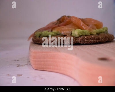 Holz Schneidebrett mit einem leckeren Avocado und Lachs Sandwich auf der Oberseite Stockfoto