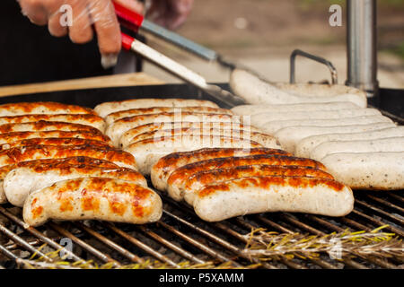 Hand mit Spachtel flips Würstchen für Hot Dogs. Stockfoto