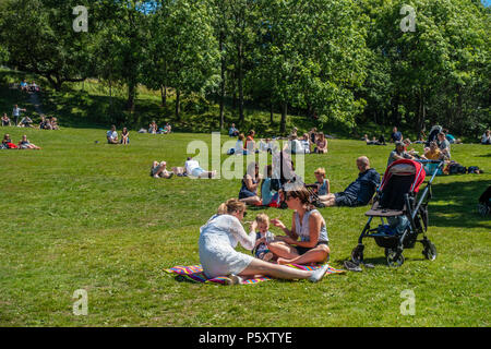 Gruppen von Menschen entspannen und genießen einen sonnigen Juni Sonntag im Kelvingrove Park im West End von Glasgow, Schottland. Stockfoto