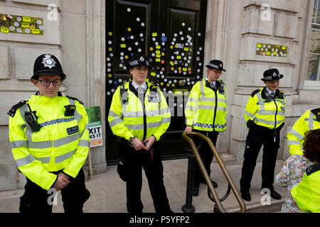 London, Großbritannien. 23. Juni 2018. Polizei schützt die Türen des Cabinet Office in Whitehall, nachdem sie mit Anti-Brexit Aufklebern geschmückt worden war - M Stockfoto