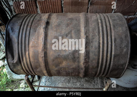 Lonely rostiges Fass. leeren Kraftstoffstand Barrel im Wald von einem Bereich mit vernachlässigt. Industrie Barrel Öl oder chemische Fässer gestapelt Stapel Ölpreis pro Barrel Stockfoto