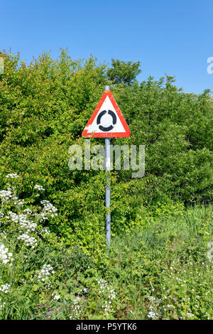 Ein Kreisverkehr Zeichen gegen eine hohe Hecke und blauer Himmel Stockfoto