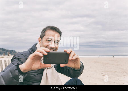Mann am Strand mit Telefon, Frankreich Stockfoto