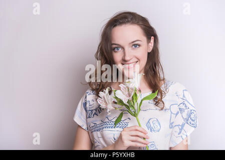 Frau mit einer Blume. Frau auf weißem Hintergrund. Ein Mädchen mit Blumen in der Hand auf einem weißen Hintergrund. Stockfoto