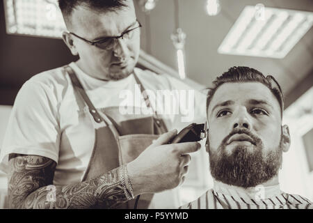 Mann beim Fräsen ein Bart in einem Barbershop in Schwarz & Weiß Stilisierung Stockfoto