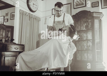 Friseur während der Arbeit in seinem Friseur. Bild in Schwarz und Weiß Stilisierung Stockfoto