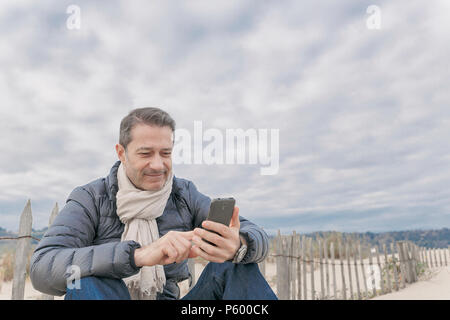 Französischen Mann am Strand mit Telefon Stockfoto