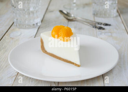 Käsekuchen mit Scheiben von Mandarin auf weiße Platte Stockfoto