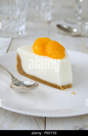 Käsekuchen mit Scheiben von Mandarin auf weiße Platte Stockfoto