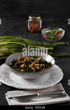 Schüssel mit gedünstetem Chicorée herzen Salat, Oliven, Sardellen, Pinienkernen, Kapern und Olivenöl. Stockfoto