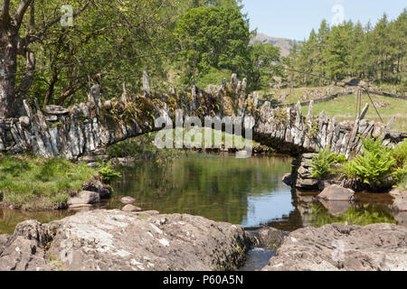 Slater's Bridge ist ein aus dem 17. Jahrhundert Fußgängerzone/Packesel schiefer Brücke über den Fluss Brathay im englischen Lake District Stockfoto