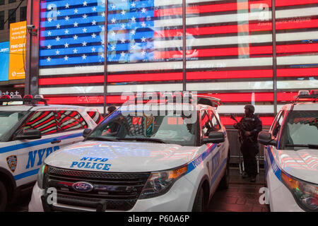 Eine bewaffnete NYPD cop steht vor einem Neon Sterne und Streifen in Times Square in New York City Stockfoto