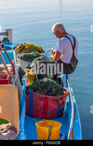 Lokale fischer Reparatur der Fischernetze auf ein traditionelles Fischerboot bis in den alten Hafen von Ayia Napa, Zypern gebunden Stockfoto