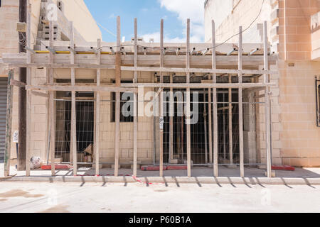 Traditionelle Holzpfähle als Unterstützung Gerüst an einem Haus home Baustelle in Malta verwendet. Stockfoto
