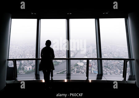 Silhouette einer Frau mit Blick auf die Stadt außerhalb eines Fensters in Tokio skytree. Stockfoto