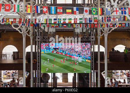 VALLETTA, MALTA - 24. JUNI 2018: Große LCD-Fernseher mit live Übertragung eines Fußballspiels in einem Sports Pub, geschmückt mit Fahnen von countrie Stockfoto