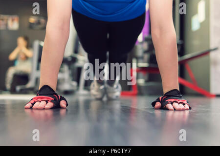 Nahaufnahme der Hand der Frau zu tun Push-ups in der Turnhalle. Ausbildung der Mädchen in der Halle. Behandschuhten Händen auf dem Boden in Nahaufnahme. mitaines. Stockfoto