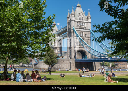 Lond, UK, 27. Juni 2018. Die hitzewelle weiter in Central London mit blauem Himmel und potenziell brechen Temperaturen erfassen. Massen von Touristen und Büroangestellten an mehr London statt und die Tower Bridge genießen das heiße Wetter und strahlendem Sonnenschein saßen auf dem Gras und Sonnenbaden. Quelle: Steve Hawkins Fotografie/Alamy leben Nachrichten Stockfoto