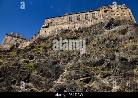 Vulkanische plug Felswand von Castle Rock mit rotem Baldrian und Großen Saal des Königlichen Palast von Edinburgh Castle mit blauem Himmel in Edinburgh, Schottland Stockfoto