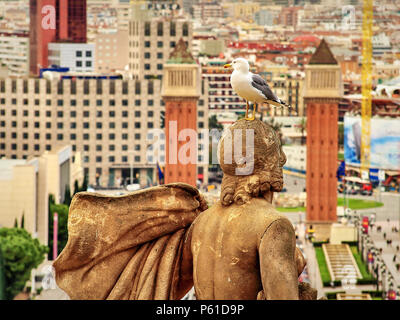 Ein Albatros auf einer der Statuen auf der Montjuic mit dem venezianischen Türmen im Hintergrund in Barcelona, Spanien Stockfoto