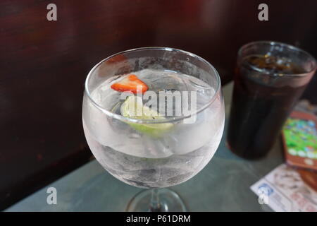 Ein Gin Tonic mit einem Soft-Drink und Handy im Hintergrund Stockfoto