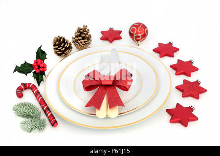 Weihnachtsessen Ort Einstellung mit Porzellan Teller, Besteck, Rot glitter Bug, Christbaumkugel Dekorationen mit Winter Stechpalme und Tanne auf weißem Hintergrund. Stockfoto