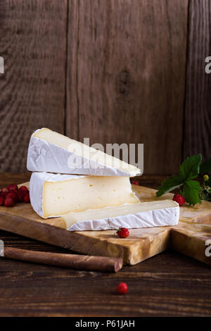 Französischer brie Käse, wilden Erdbeeren und weiß purple Wild Flower Bouquet auf ländlichen Holztisch Stockfoto