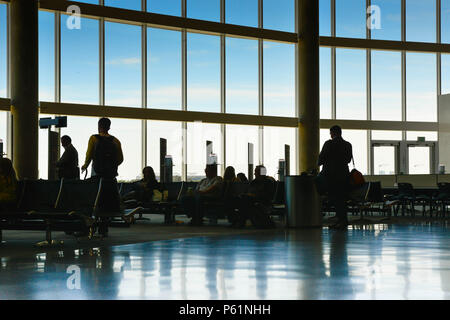 Silhouetten werden erstellt, der Passagiere oder sitzende gegen einen hellen Himmel überwältigend in Boarding Gate Bereich an eine Fluggesellschaft termi verglasten Stockfoto