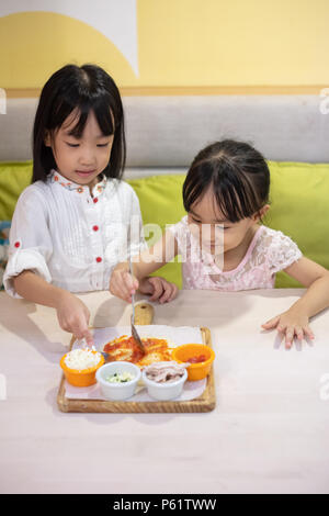 Asiatische kleinen chinesischen Mädchen DIY mini Pizza zu Hause Stockfoto