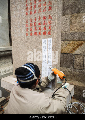 Qingdao, China - Dezember 2017: älterer Mann carving Namen und Spende auf s im Taiqing Tempel Stele, Laoshan Stockfoto