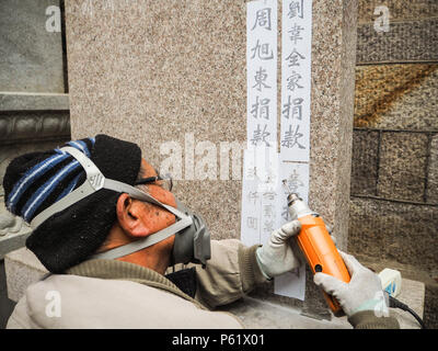 Qingdao, China - Dezember 2017: älterer Mann carving Namen und Spende auf s im Taiqing Tempel Stele, Laoshan Stockfoto