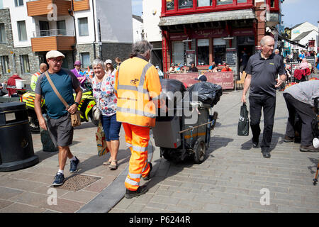 Street cleaner tragen Gut sichtbare Kleidung schieben bin Warenkorb in Keswick, Lake District, Cumbria England Großbritannien Stockfoto