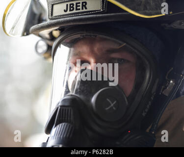 Us Air Force Airman 1st Class Grant Kopplin, einem Brand Protection Specialist auf die 673Rd Bauingenieur Geschwader zugewiesen, blickt in die Kamera während der Durchführung der Brandbekämpfung bohrt mit Joint Base Elmendorf-Richardson, Alaska, 13. April 2016. Die JBER Feuerwehr ist ausgebildet in verschiedenen Notsituationen zu reagieren und leitet regelmäßig sustainment Übungen Kenntnisse und Einsatzbereitschaft aufrecht zu erhalten. (U.S. Air Force Foto/Alejandro Pena) Stockfoto